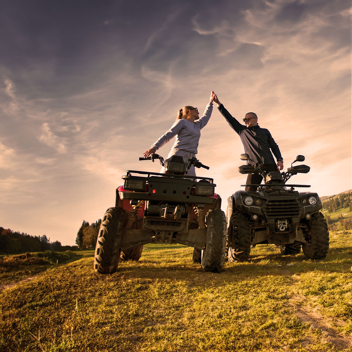 Two people riding their own atv powered by Batteries Plus powersport battery, giving a high-five Two people riding their own atv powered by Batteries Plus powersport battery, giving a high-five