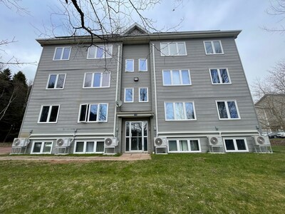 Front of grey student housing building in Sackville, N.B., with blue sky and grass. (CNW Group/Canada Infrastructure Bank)