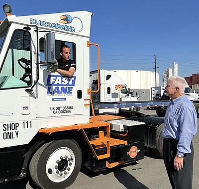 Henry Wilson, seated in the Orange EV terminal truck, speaks with his father, Patrick Wilson, President of Fast Lane Transportation, at their Wilmington, CA location.