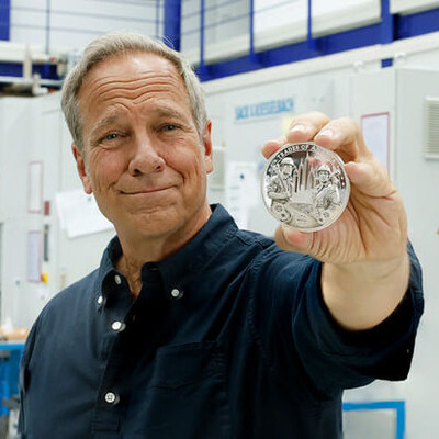 Mike Rowe holding the "Trades of America" coin.