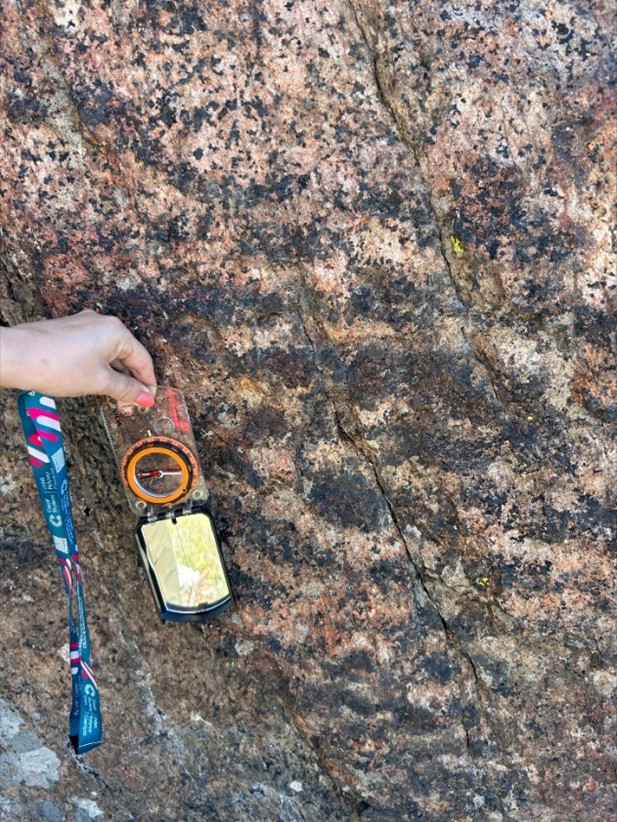 A hand holding a compass on a rock AI-generated content may be incorrect.