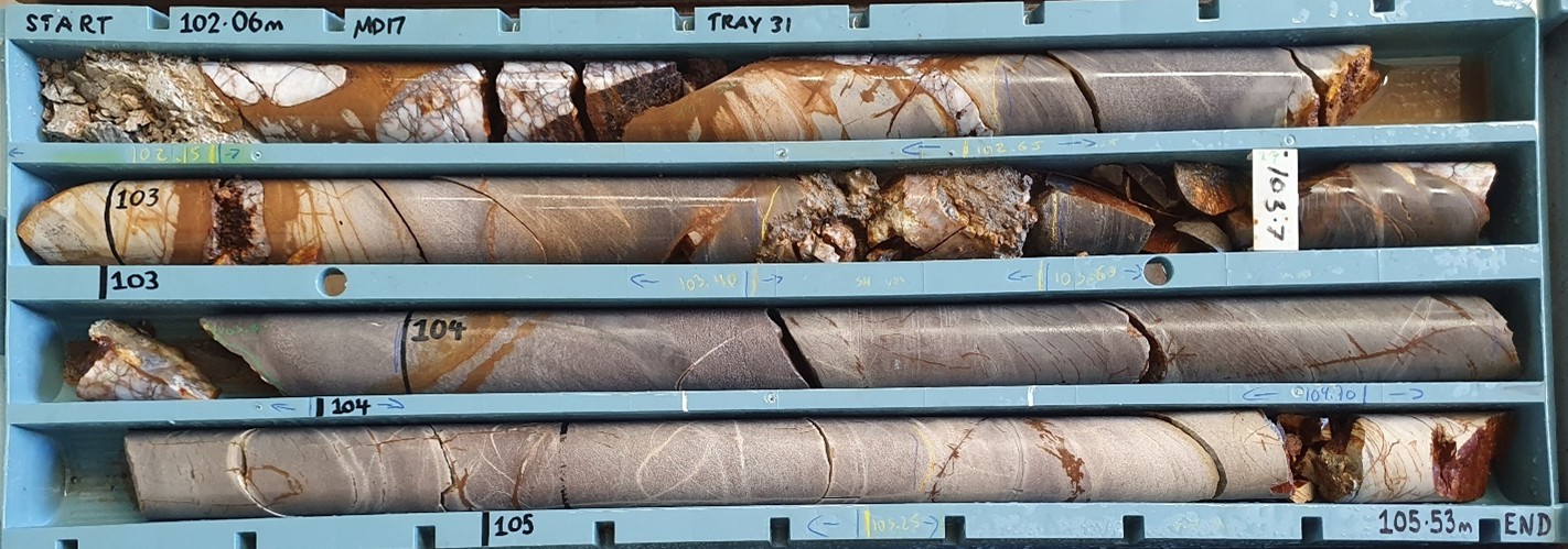 MD17 (102.06 m–105.53 m). Interpreted Western Domain Fault between 102.06 m and 103.6 m. Significant intersection of 0.95 m @ 10.0 g/t Au from 102.65 m with elevated arsenic returned from this intervalb.