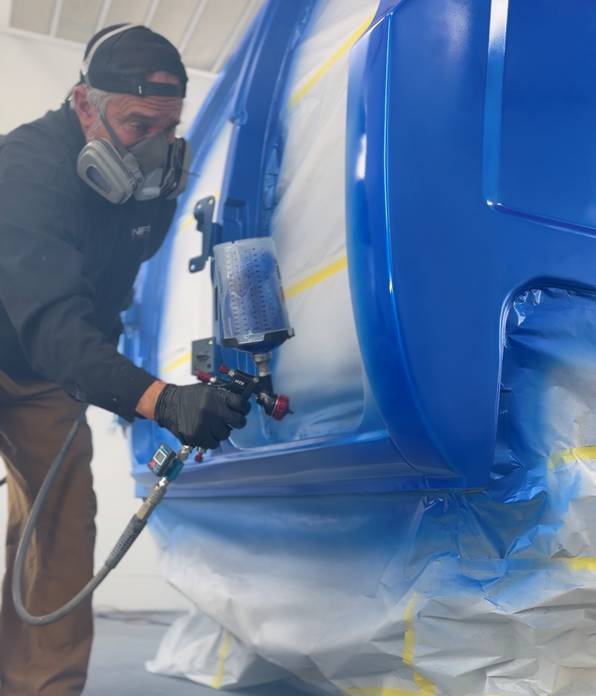 NFI Empire painter in respirator spraying blue paint on Project REBORN-001